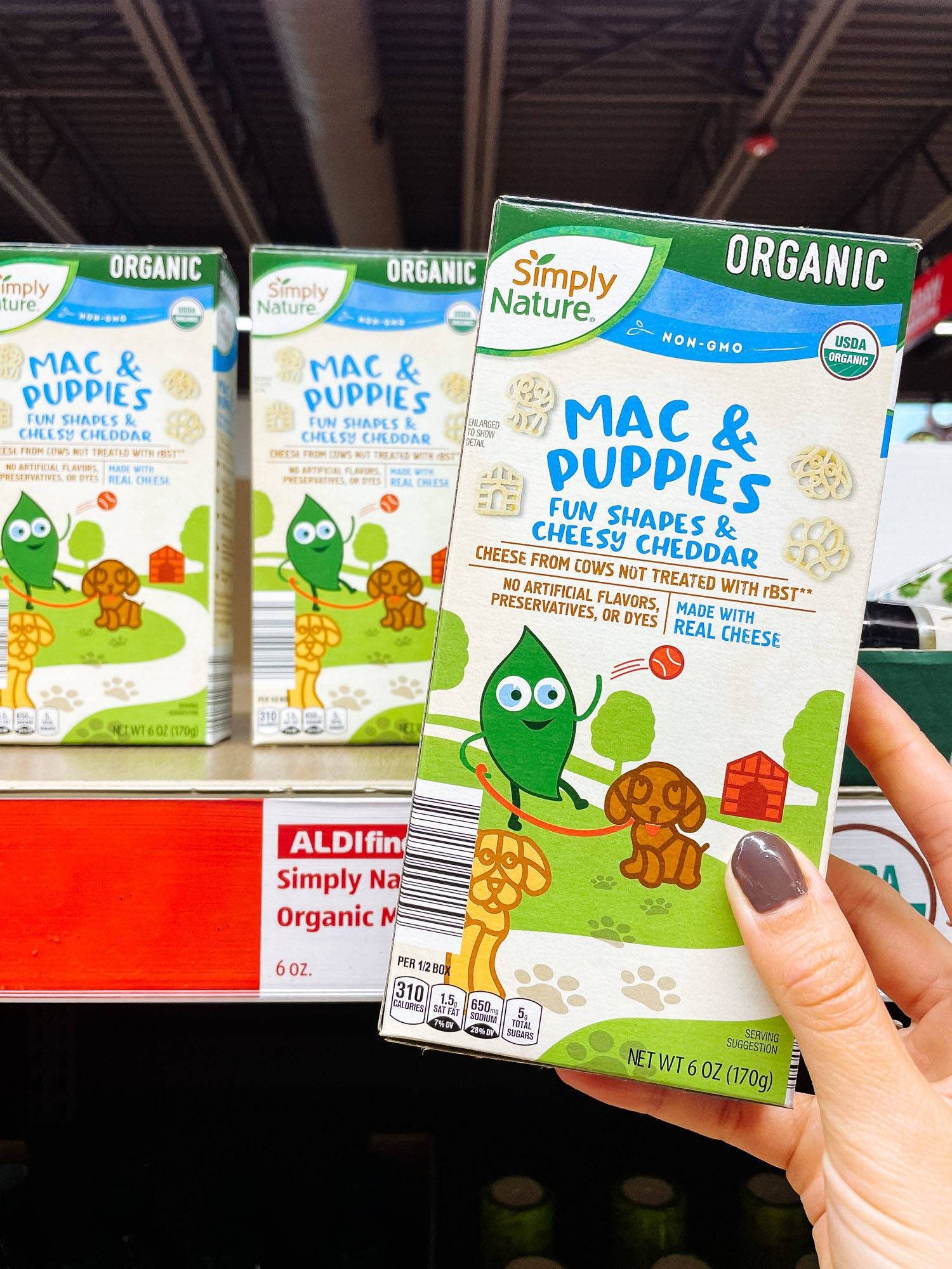 White hand holding boxed mac and cheese from ALDI.