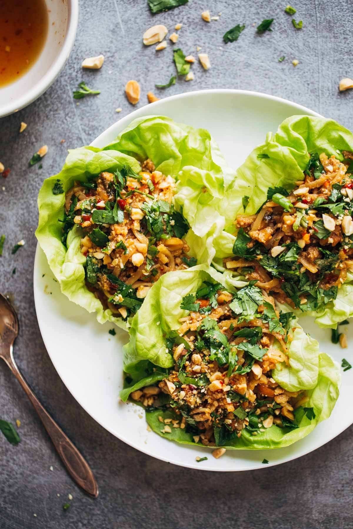 Peanut Chicken Lettuce Wraps with a Ginger Garlic sauce on a white plate.