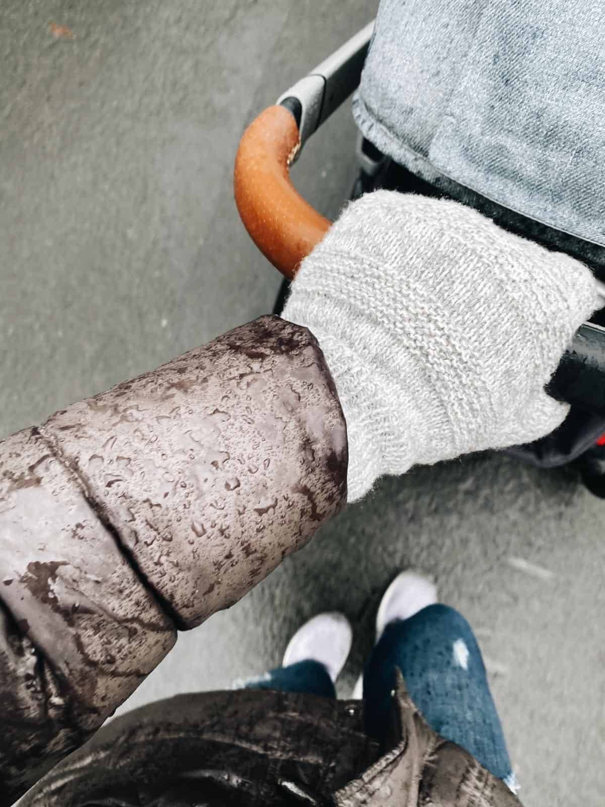 A hand pushing a stroller in the winter.