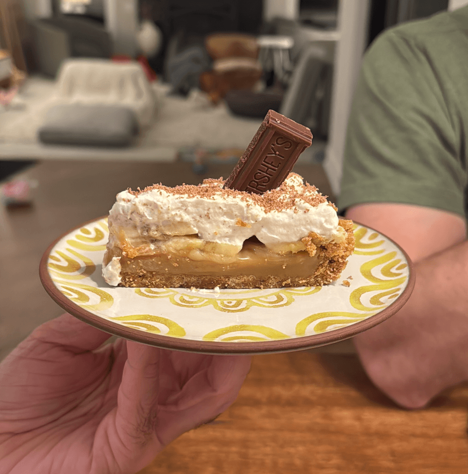 Banoffee pie on a plate with chocolate square on top.