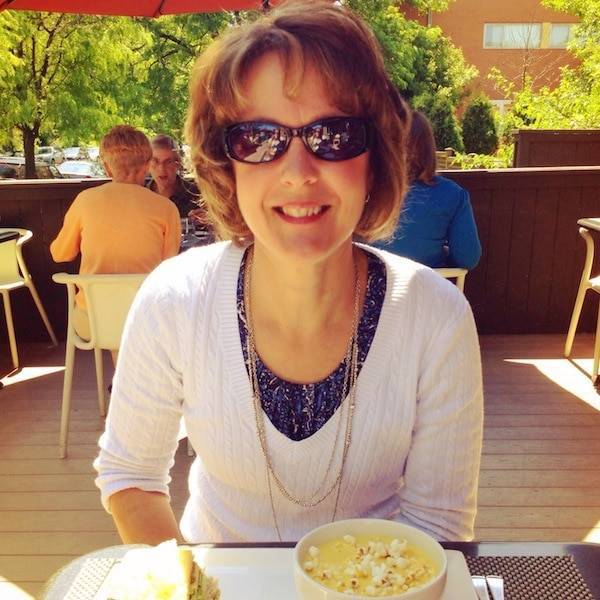 Woman wearing sunglasses smiling at the camera.