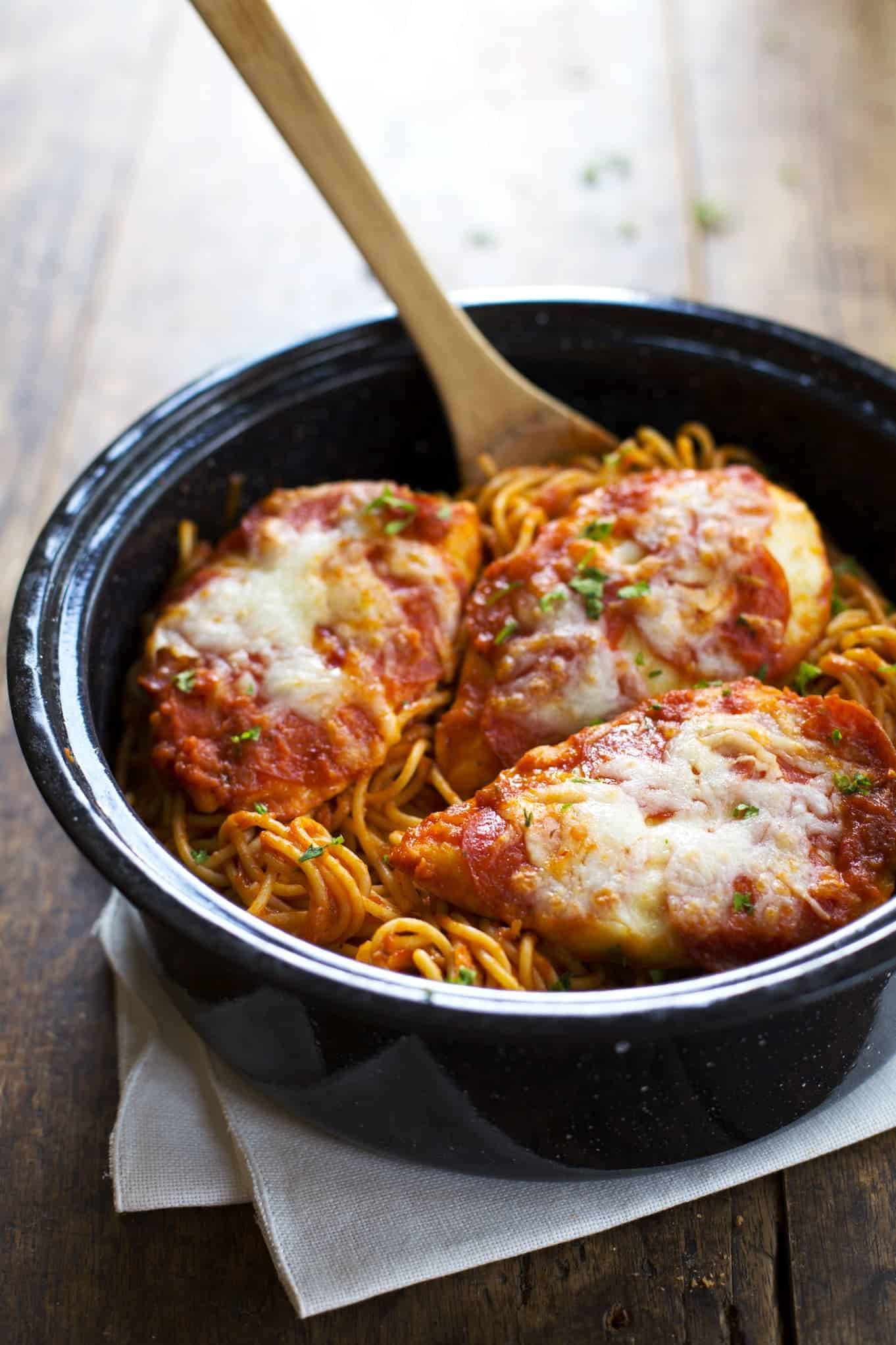 Chicken Pizzaiola in a black dish with a wooden spoon.