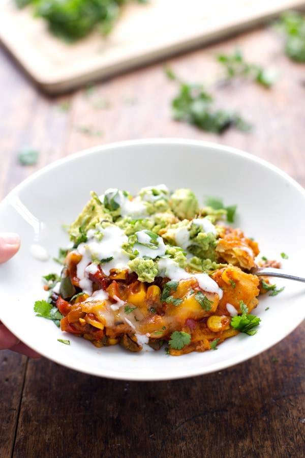 Mexican casserole in a bowl with a fork and guacamole.
