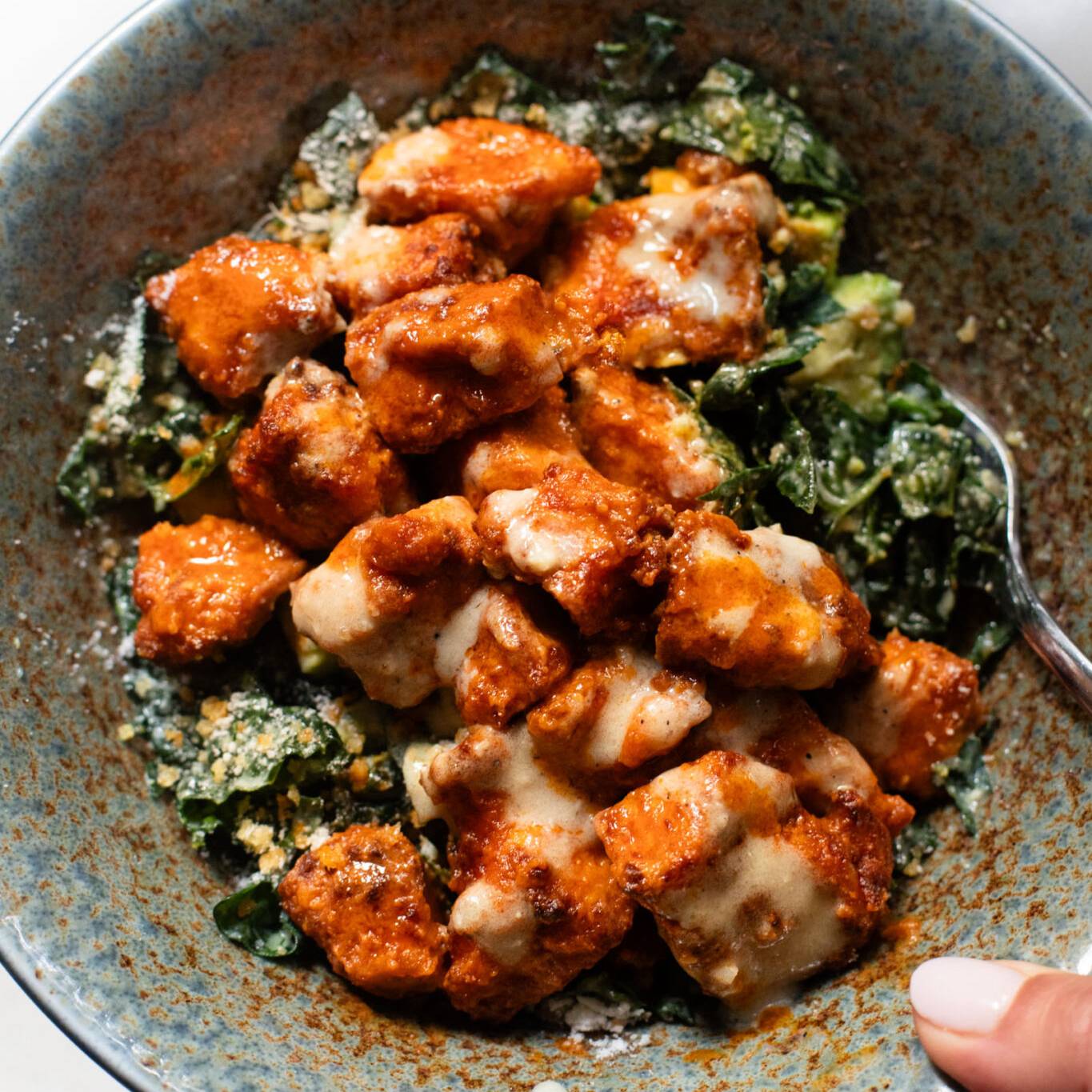 Buffalo tofu in a bowl with kale caesar salad.