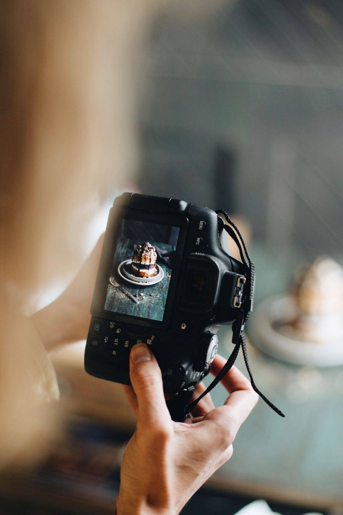 Hands holding a camera taking a photo of food.