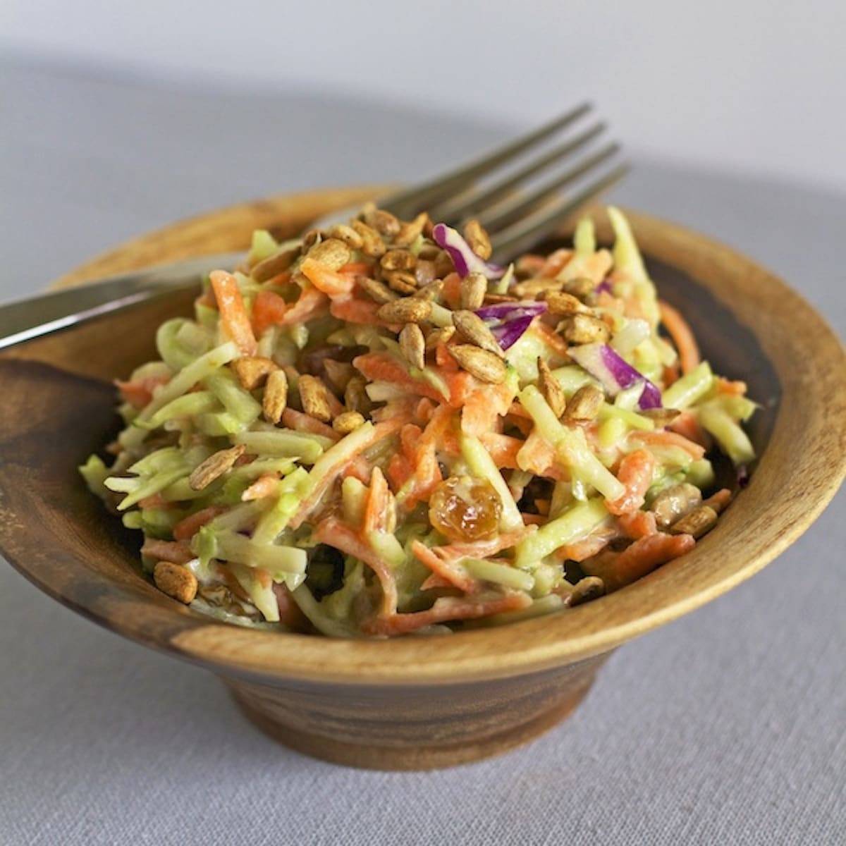 Green curry salad in a wooden bowl with a fork.
