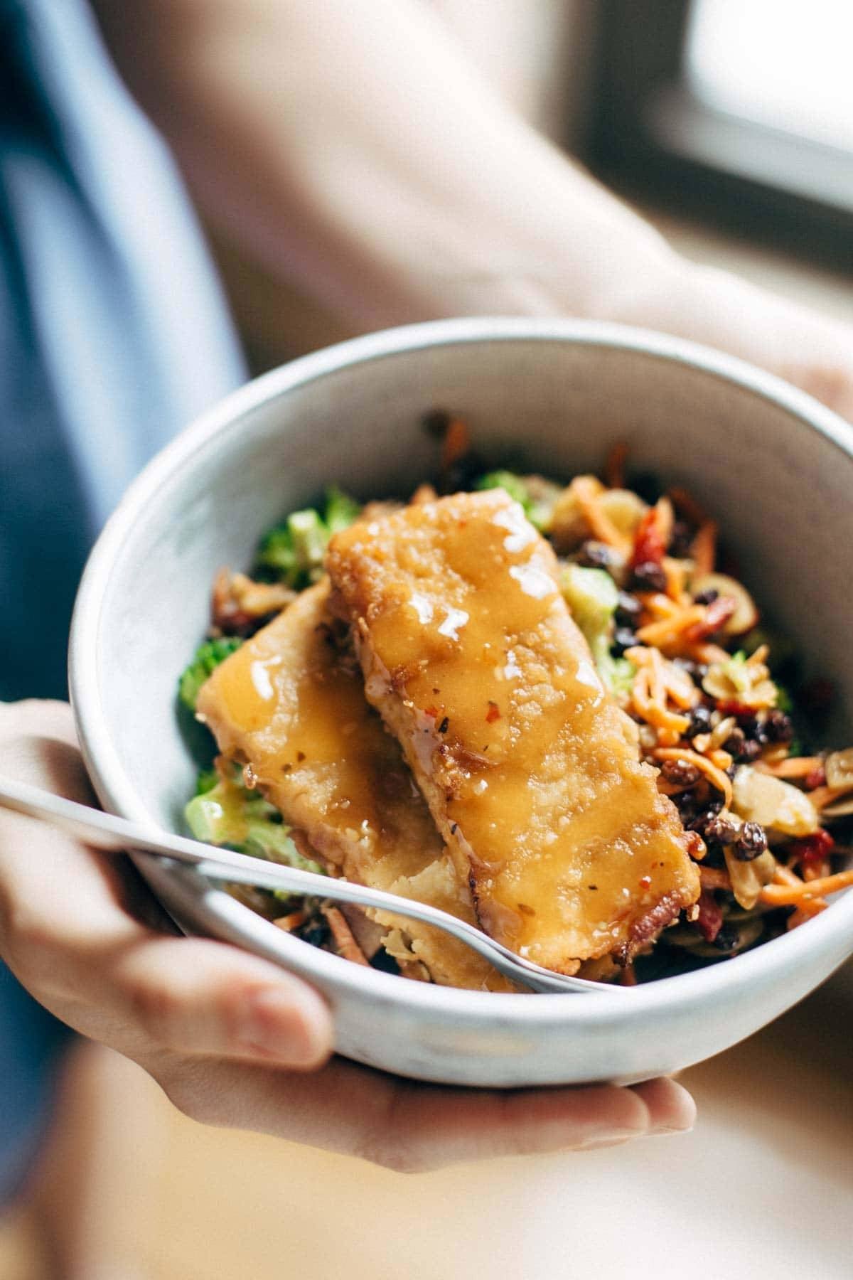 Hands holding a bowl of food.
