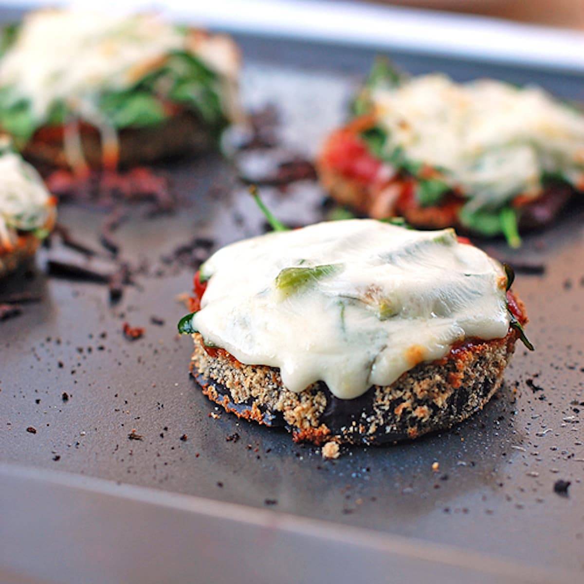 Eggplant pizzas topped with marinara and melted cheese.